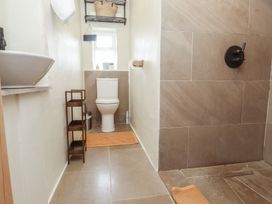 A bathroom with a toilet sink shower area and shelves at Bryn Canaid in Uwchmynydd near Aberdaron