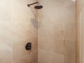 A tiled shower with a wall-mounted showerhead and a control handle at Bryn Canaid in Uwchmynydd near Aberdaron