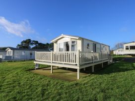 A mobile home with a white railing deck on a grassy area with other mobile homes nearby at Bay View in Hillway near Bembridge
