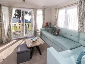 A living room with a light blue sectional sofa a wooden coffee table and sliding glass doors leading to a deck at Bay View in Hillway near Bembridge