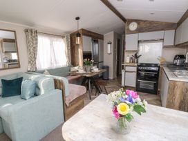 A kitchen and dining area with a stove table flowers and seating at Bay View in Hillway near Bembridge