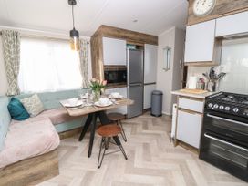 A kitchen and dining area with a corner bench sofa a table set for four a refrigerator stove and kitchen utensils at Bay View in Hillway near Bembridge