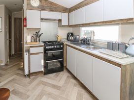 A kitchen with a stove sink toaster kettle and storage cabinets at Bay View Hillway near Bembridge