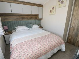 A bedroom with a double bed pillows a patterned blanket bedside tables and wall cabinets at Bay View Hillway near Bembridge