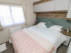A bedroom with a double bed a window with curtains bedside tables and overhead cabinets at Bay View in Hillway near Bembridge