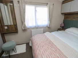 A bedroom with a bed side table and lamp near a window with curtains at Bay View in Hillway near Bembridge