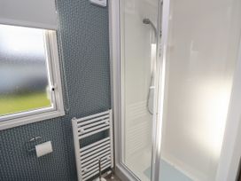 A bathroom with a shower enclosure a towel radiator a window and a toilet paper holder at Bay View in Hillway near Bembridge