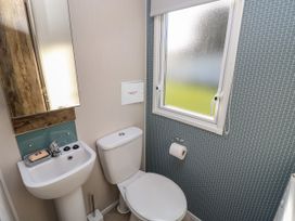 A bathroom with a toilet sink mirror and a window at Bay View in Hillway near Bembridge