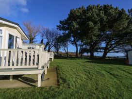 A grassy lawn with trees and a terrace of a mobile home at Bay View in Hillway near Bembridge