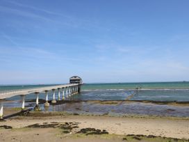 A long pier extending over a sandy beach and shallow water to a building at Bay View in Hillway near Bembridge