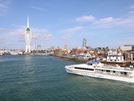 A ferry boat in the water near a city with buildings and a tall tower at Bay View in Hillway near Bembridge