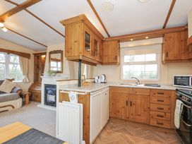 A kitchen with wooden cabinets and appliances at Little Malory in St Giles-On-The-Heath