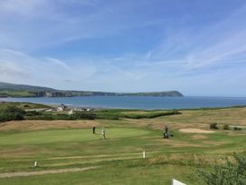 A golf course near the coast with people playing golf and a beach in the background at Glanduad Fawr in Newport Pembrokeshire