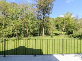 A grassy yard with a metal fence in front of trees and a blue sky at Glanduad Fawr in Newport Pembrokeshire