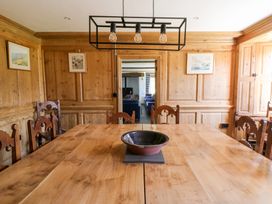 A dining room with a wooden table and chairs a bowl on the table wood paneled walls and framed pictures at Glanduad Fawr in Newport Pembrokeshire