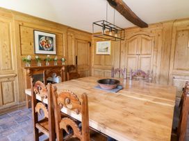A dining room with a wooden table and chairs wooden paneled walls and framed artwork at Glanduad Fawr in Newport Pembrokeshire