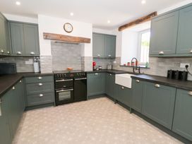 A kitchen with green cabinets a black oven a farmhouse sink and a clock on the wall at Glanduad Fawr in Newport Pembrokeshire