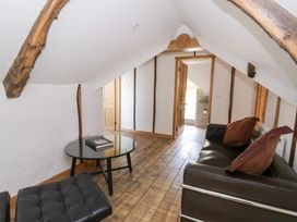 A small sitting area with a black sofa, cushions, a glass coffee table, and wooden floorboards at Glanduad Fawr in Newport Pembrokeshire