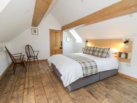 A bedroom with a bed with patterned pillows and two wooden chairs on wooden flooring at Glanduad Fawr in Newport Pembrokeshire
