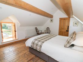 A bedroom with a bed two wooden chairs a wooden door and a window with wooden shutters at Glanduad Fawr in Newport Pembrokeshire