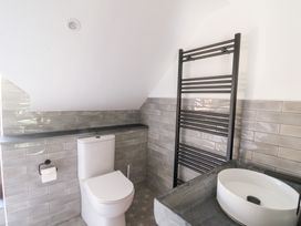 A bathroom with a toilet a black towel rack and a white sink on a countertop at Glanduad Fawr in Newport Pembrokeshire