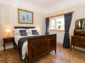 A bedroom with a wooden bed a nightstand with lamps a window with curtains and a wooden dresser with a mirror at Glanduad Fawr in Newport Pembrokeshire