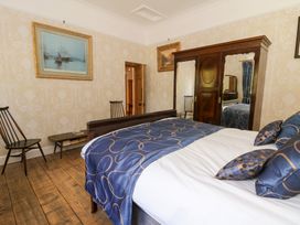 A bedroom with a wooden bed blue bedding wooden wardrobe with mirrors chairs and paintings at Glanduad Fawr in Newport Pembrokeshire