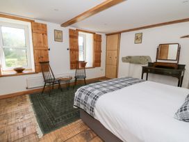 A bedroom with a bed two chairs a small table a wardrobe and a dressing table at Glanduad Fawr in Newport Pembrokeshire
