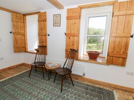 A room with two wooden chairs a small round table and windows with wooden shutters at Glanduad Fawr in Newport Pembrokeshire