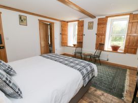 A bedroom with a bed a rug two chairs and two windows with wooden shutters at Glanduad Fawr in Newport Pembrokeshire