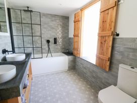 A bathroom with a bathtub shower combination double sink vanity wooden window shutters and a toilet at Glanduad Fawr in Newport Pembrokeshire