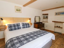 A bedroom with a double bed wooden floor wooden beams a dresser with mirror and shelves at Glanduad Fawr in Newport Pembrokeshire