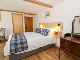 A bedroom with a bed with patterned pillows and runner a wooden chest of drawers and a chair at Glanduad Fawr in Newport Pembrokeshire