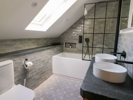 A bathroom with a skylight above a bathtub and two sinks on a counter at Glanduad Fawr in Newport Pembrokeshire