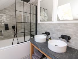 A bathroom with double sinks and black fixtures next to a bathtub with a glass shower screen at Glanduad Fawr in Newport Pembrokeshire