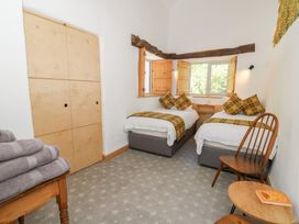 A bedroom with two single beds with patterned cushions and throws a wooden chair a small round table and folded towels on a wooden table at Glanduad Fawr in Newport Pembrokeshire
