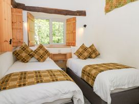 A bedroom with two single beds with patterned cushions and throws near a window at Glanduad Fawr in Newport Pembrokeshire