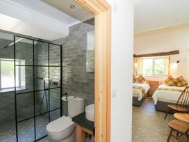 A bathroom with a toilet and glass shower and a bedroom with two single beds at Glanduad Fawr in Newport Pembrokeshire