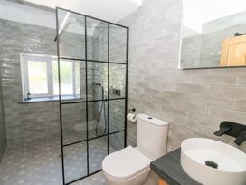 A bathroom with a shower area separated by a glass partition a toilet and a round sink on a countertop at Glanduad Fawr in Newport Pembrokeshire