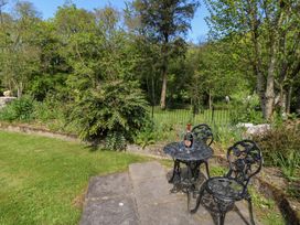 A garden seating area with a black metal table and two chairs on a stone patio at Glanduad Fawr in Newport Pembrokeshire