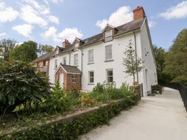 A white multi-story house with dormer windows and a brick porch in a garden at Glanduad Fawr in Newport Pembrokeshire