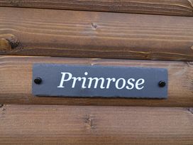 A wooden wall with a slate sign that reads Primrose at Primrose in Higher Wambrook near Chard