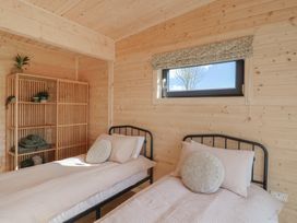 A bedroom with two single beds and a wooden shelf with plants and towels at Primrose in Higher Wambrook near Chard