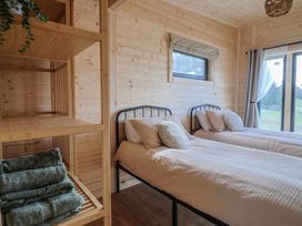 A bedroom with two single beds and folded towels on a wooden shelf at Primrose in Higher Wambrook near Chard