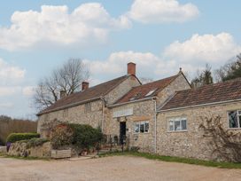 Stone building with multiple chimneys and potted plants near entrance at Primrose in Higher Wambrook near Chard