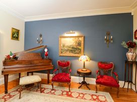 A living room with a grand piano and red chairs at the White House