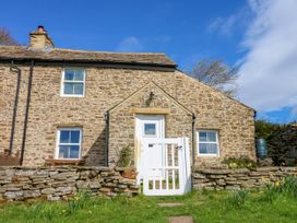 A stone house with a white wooden gate and grass in front at Swinhope View in Hexham