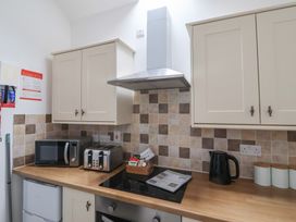 A kitchen with a microwave, toaster, electric kettle, stovetop, and cabinets at Gannet in Flamborough