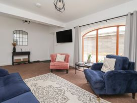 A living room with a blue sofa and a pink armchair at Razorbill in Flamborough
