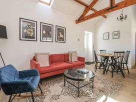 A living room with a red sofa blue rocking chair round glass coffee table and dining table with black chairs at Guillemot in Flamborough